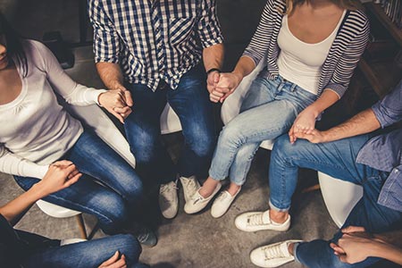 Teens holding hands at support group meeting