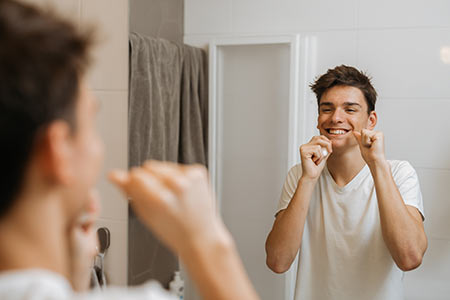 Teen boy flossing in mirror