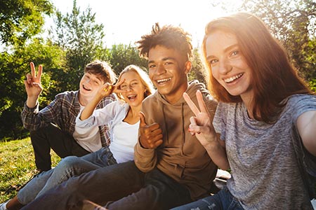 Group of teens smiling at the camera with hands in the shape of peace signs