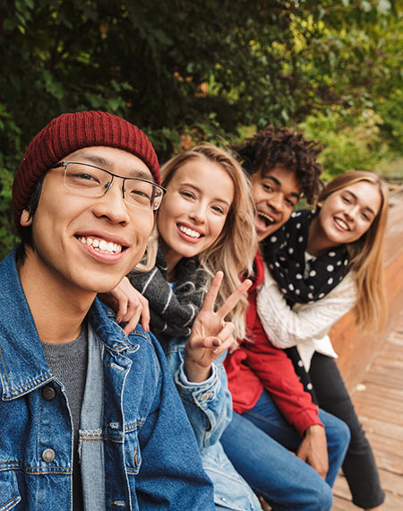Teens sitting together outdoors smiling at the camera